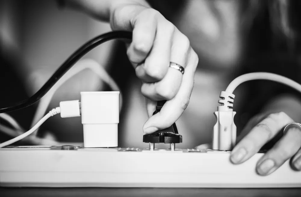 Hände stecken einen Stecker in eine Steckdosenleiste